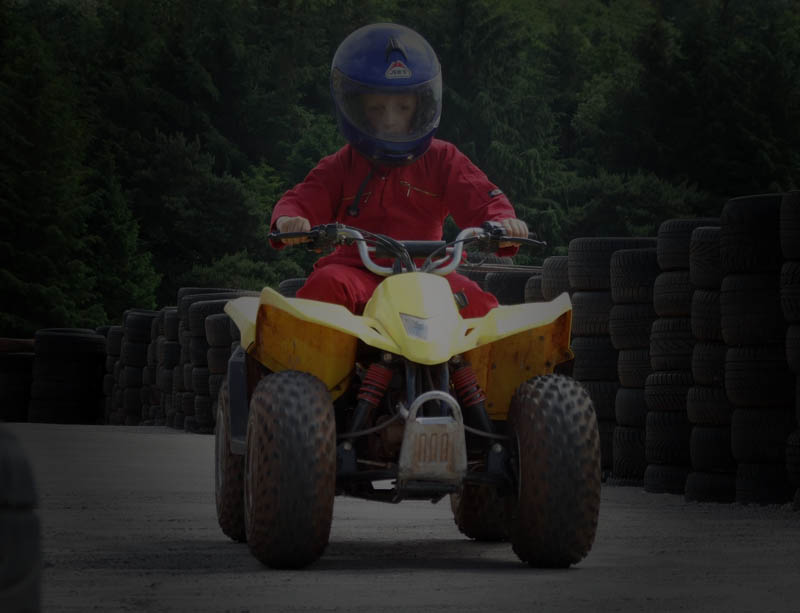 A photograph of a child riding a quad bike into a corner